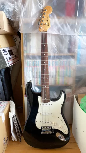 写真:雑然とした物置部屋に置かれたPhotogenic(安ギター)の黒いストラトキャスター