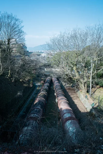 写真：蹴上放水所の上から太い水道管を撮影。平安神宮方面の京都の町並みが見える。
